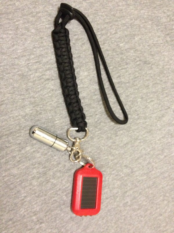 Black paracord keychain with a red solar LED light and a silver peanut lighter